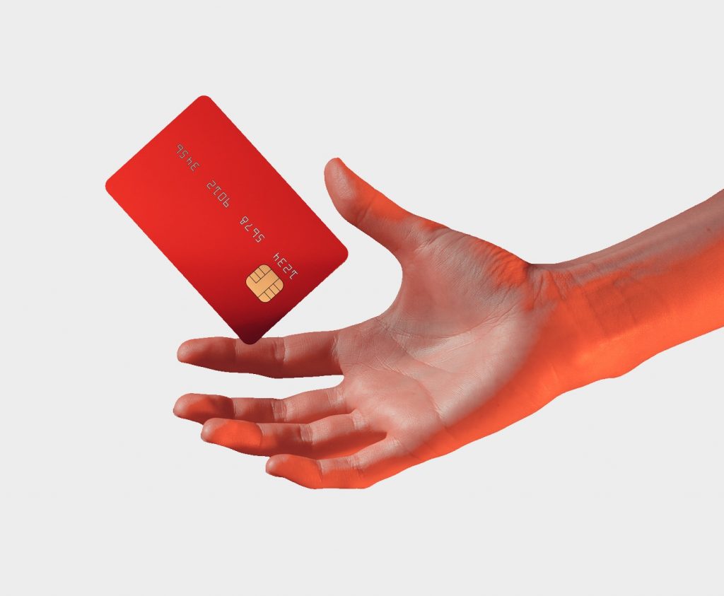 Nahaufnahme weibliche Hand hält schwebende Debitkarte auf grauem Hintergrund debit-karte.com